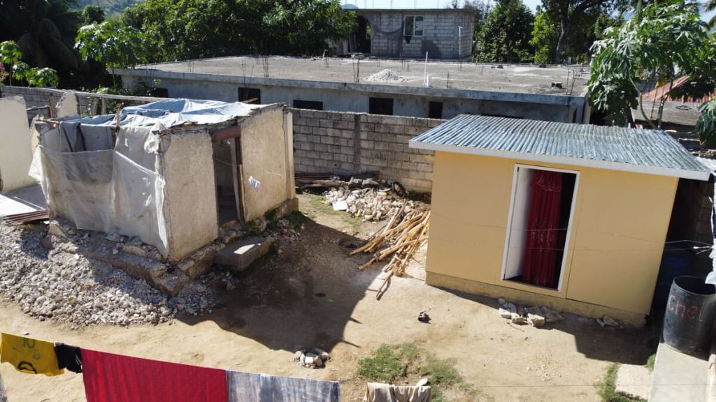 Two homes side by side, one is destroyed and the other is newly built